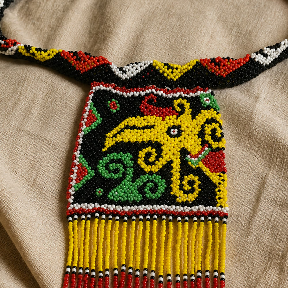 Macro detail of a yellow bird-like beaded form surrounded by green curls and red accents