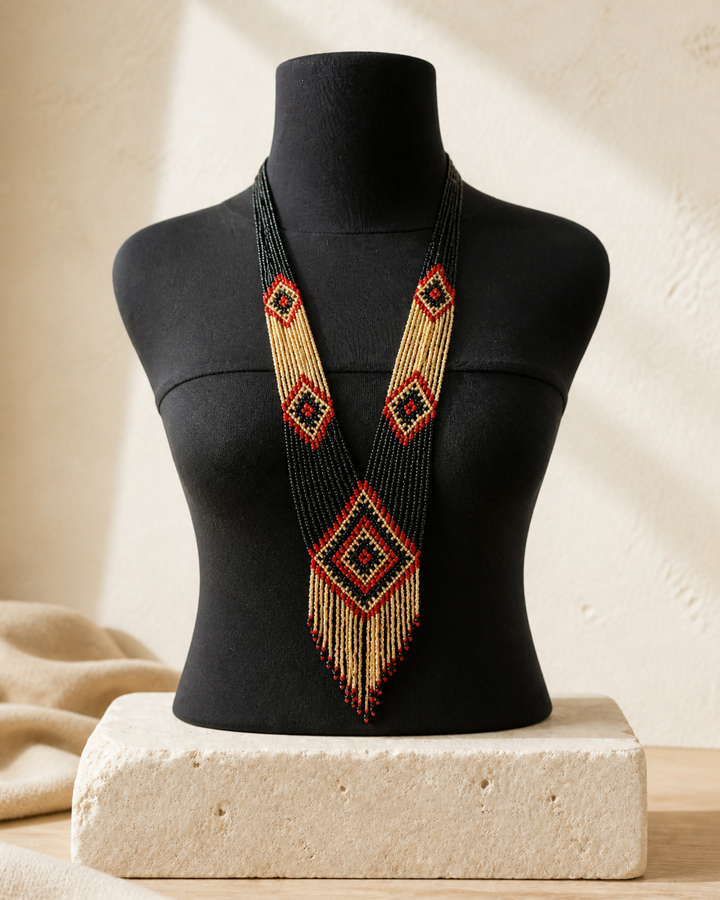 Gold, red and black Ketupat beaded necklace on a black mannequin in a warm cream studio