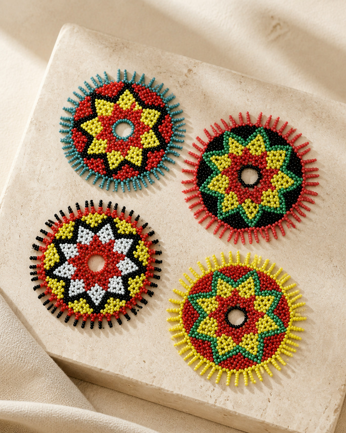Four round beaded coasters with distinct floral-star patterns